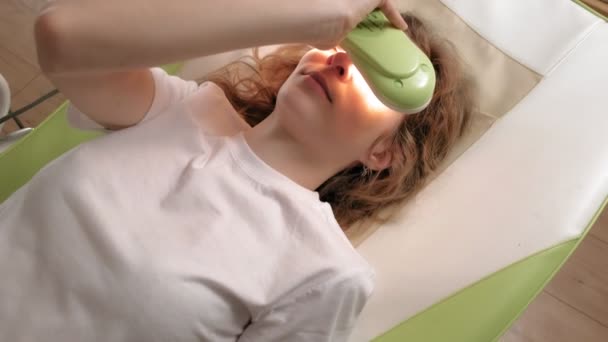 A woman lies on a massage bed with jade rollers. - Footage, Video