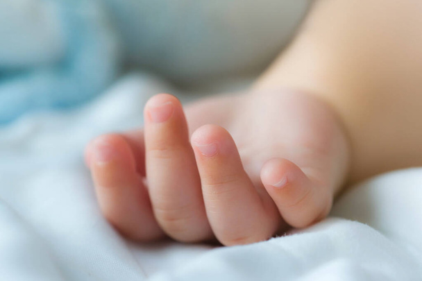crop of hand and fingers,a newborn Asian baby boy sleep on the bed , selective focus - Fotó, kép