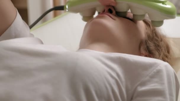 Een vrouw ligt op een massagebed met jade rollers. - Video