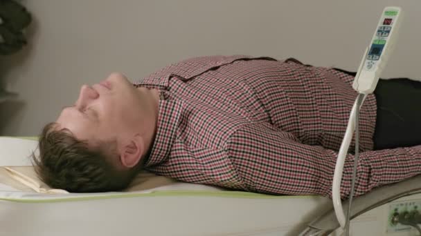 Ein Mann liegt auf einem Massagebett mit Jadewalzen. - Filmmaterial, Video