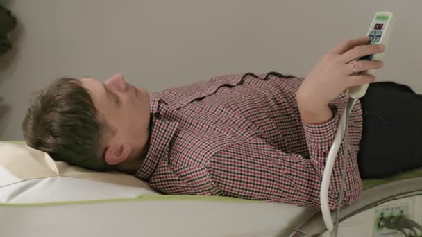 Un hombre se acuesta en una cama de masaje con rodillos de jade
. - Imágenes, Vídeo
