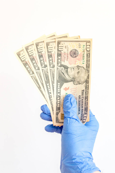 10 US dollar banknotes in hand in surgical gloves. USD banknote with portrait of Alexander Hamilton. Covid-19 Coronavirus outbreak. Concept of stop and protect Covid-19 concept. - Foto, immagini