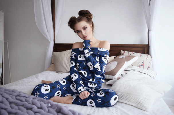 a girl in home clothes, pajamas with a beautiful print. at home, resting in a bright interior. cute, sexy, fashionable, posing, with makeup and hair styling - Фото, изображение