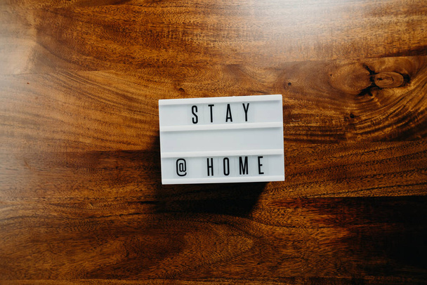 'Stay @ home' κείμενο σε light box σε ξύλινο φόντο. - Φωτογραφία, εικόνα