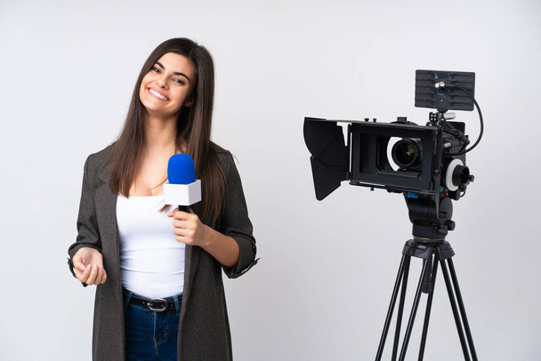 Δημοσιογράφος κρατώντας ένα μικρόφωνο και αναφέροντας ειδήσεις σε απομονωμένο λευκό φόντο - Φωτογραφία, εικόνα