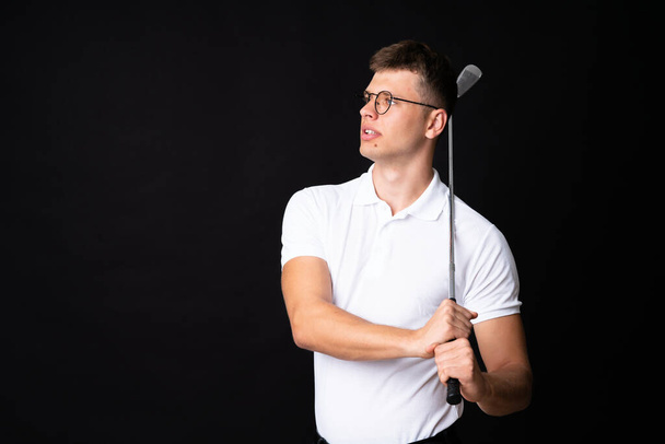 Handsome young golfer player man over isolated black background - Fotó, kép