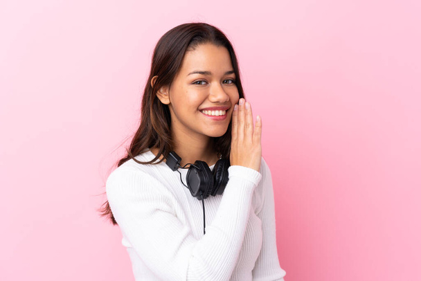Nuori nainen kuulokkeet yli eristetty vaaleanpunainen seinä kuiskaa jotain
 - Valokuva, kuva