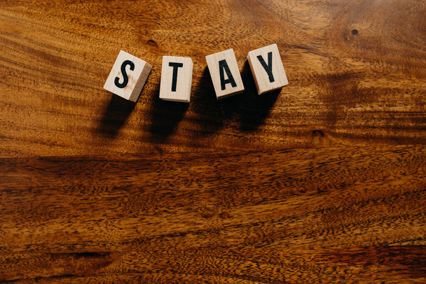 Tekst "Stay" wykonany z drewnianej kostki na drewnianym tle. - Zdjęcie, obraz