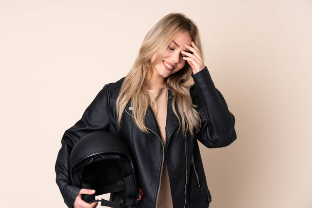 Russian girl with a motorcycle helmet isolated on beige background laughing - Фото, изображение