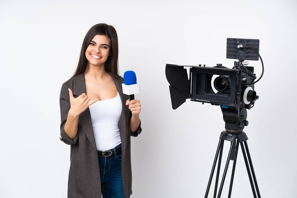 Verslaggever vrouw met een microfoon en het rapporteren van nieuws over geïsoleerde witte achtergrond maken telefoon gebaar - Foto, afbeelding