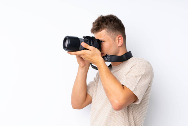Fiatal jóképű férfi elszigetelt fehér háttér egy professzionális kamera - Fotó, kép