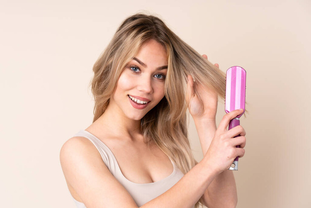 Teenager blondýny dívka s vlasy hřeben přes izolované pozadí - Fotografie, Obrázek