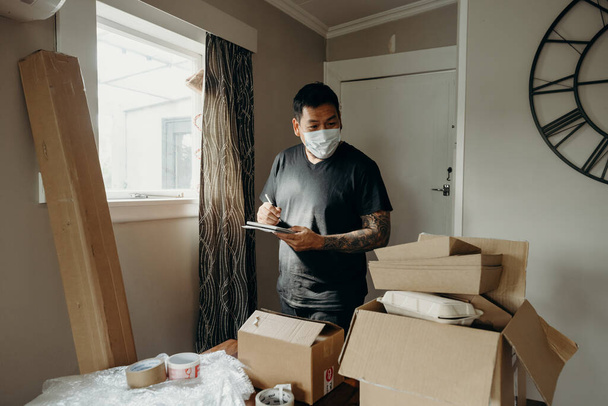 A man with tattoo as the seller prepares the delivery box for the customer, online sales, or ecommerce. Online shopping concepts. Checking an order. - Foto, afbeelding