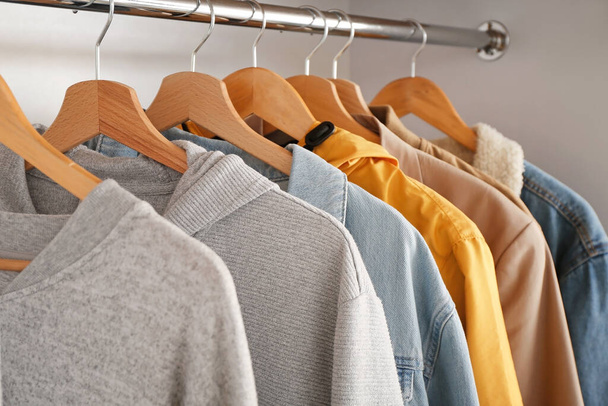 Стильная мужская одежда на вешалке в гардеробе
 - Фото, изображение