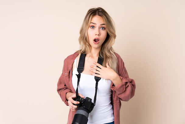 jong fotograaf meisje over geïsoleerde achtergrond verrast en geschokt terwijl rechts kijken - Foto, afbeelding