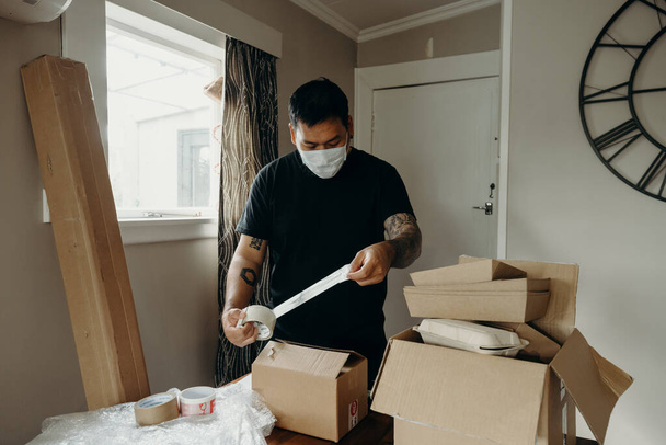 A man with tattoo as the seller prepares the delivery box for the customer, online sales, or ecommerce. Online shopping concepts. Packing the parcel. - Foto, Imagen