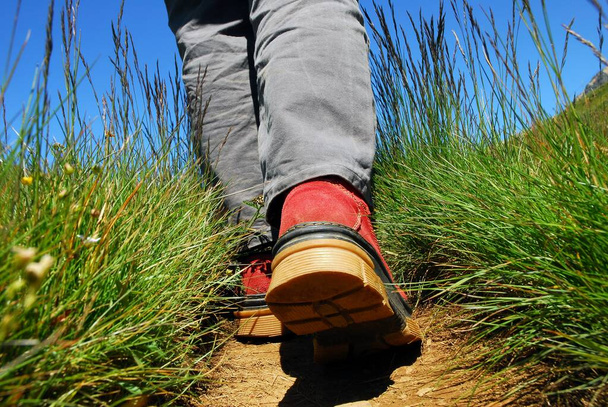 Túrázás koncepció az Alpokban egy közeli kép a gyalogos cipő az úton  - Fotó, kép