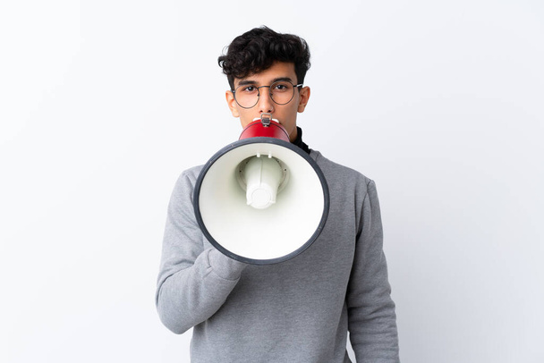 Mladý argentinský muž na izolovaném bílém pozadí křičí přes megafon - Fotografie, Obrázek