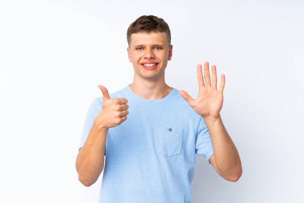 Jonge knappe man over geïsoleerde witte achtergrond tellen zes met vingers - Foto, afbeelding
