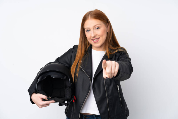 Mujer pelirroja joven con un casco de motocicleta sobre fondo blanco aislado apunta con el dedo a usted con una expresión de confianza
 - Foto, Imagen
