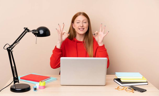 Fiatal diák nő egy munkahelyen egy laptop zen pózban - Fotó, kép