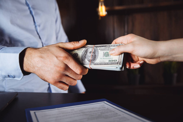 Man offering batch of hundred dollar bills. Hands close up. Venality, bribe, corruption concept. Hand giving money - United States Dollars or USD . Hand receiving money from businessman. - Фото, изображение