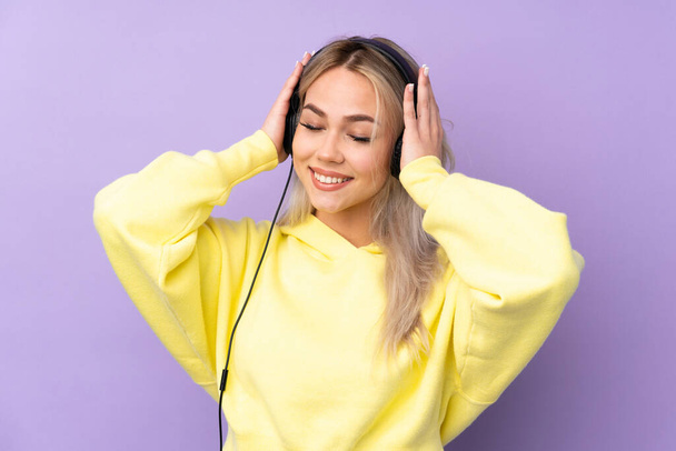 Teenager lány felett elszigetelt lila háttér hallgat zenét - Fotó, kép