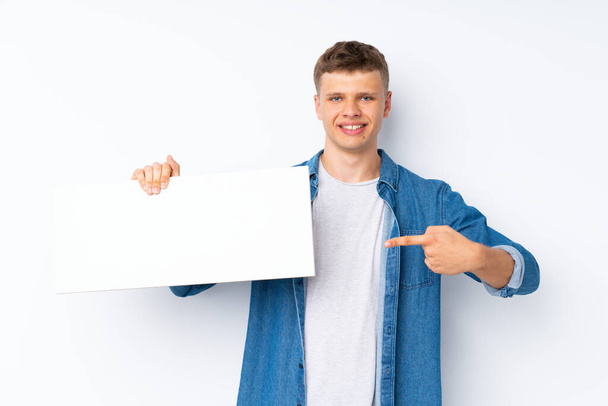 Young handsome man over isolated white background holding an empty white placard for insert a concept - Foto, Imagen
