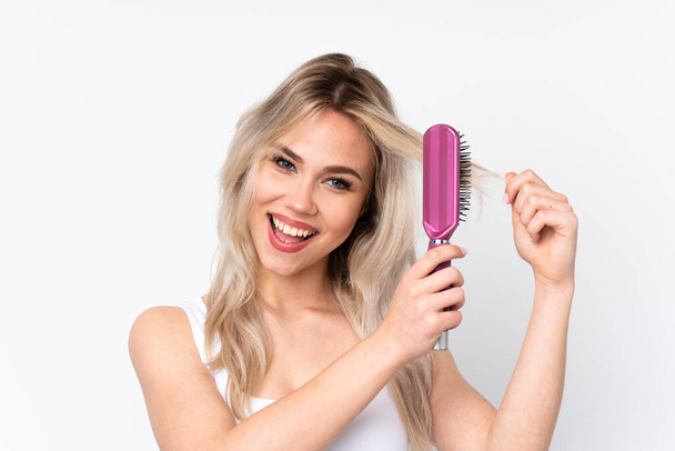 Teenager blonde girl over isolated white background with hair comb and singing - Foto, immagini