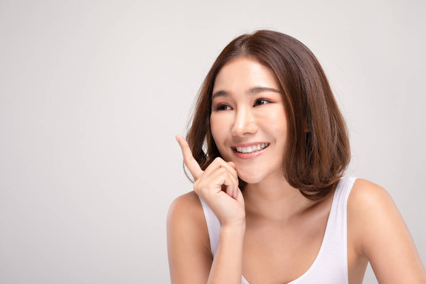 Hermosa mujer asiática con el pelo corto mirando la sonrisa de la cámara con la piel limpia y fresca Felicidad y alegre con emocional positivo, aislado en el fondo gris, concepto de belleza y cosméticos
 - Foto, imagen