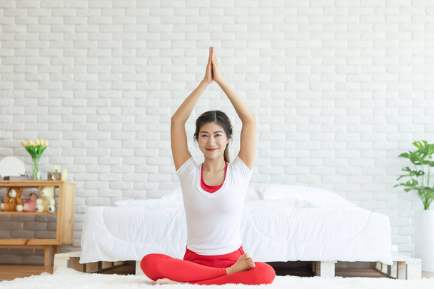 Ελκυστική ασιατική γυναίκα πρακτική yoga lotus θέτουν σε διαλογισμό στο υπνοδωμάτιο μετά ξυπνήσει το πρωί Αίσθημα τόσο άνετα και να χαλαρώσετε, Healthcare Concept - Φωτογραφία, εικόνα