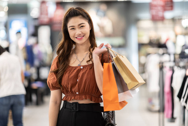 美しい魅力的な幸せなアジアの女性の笑顔とショッピングモール、ショッピングコンセプトで買い物袋でお楽しみください - 写真・画像