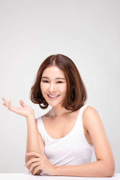 Hermosa atractiva encantadora mujer asiática sonrisa con dientes blancos mano abierta palma para mostrar cosméticos producto alegre con piel sana, aislado sobre fondo blanco, concepto de cosméticos de belleza - Foto, imagen