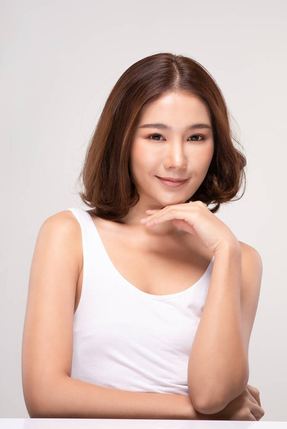 Beautiful Young Asian Woman with short hair Looking While Touching Chin feeling so happy and cheerful with healthy Clean and Fresh skin,isolated on gray background,Beauty Cosmetics Concept - Foto, immagini
