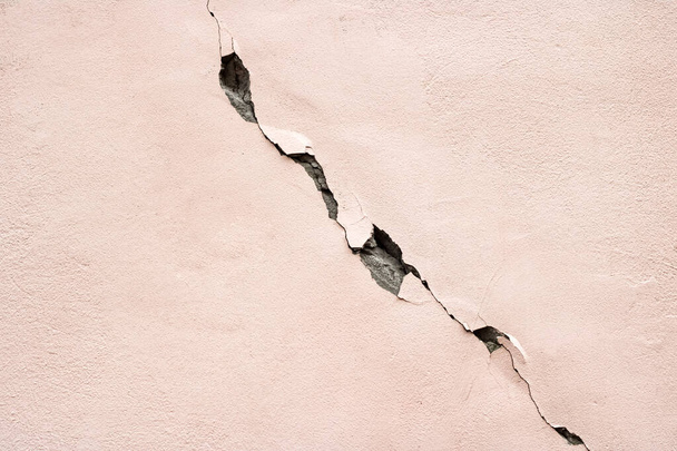 Egy nagy repedés a rózsaszín falon közelről - Fotó, kép