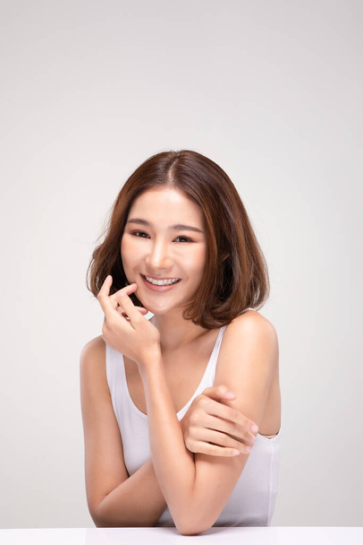 Beautiful Young Asian Woman with short hairs Touching Shoulder feeling so happy and cheerful with healthy Clean and Fresh skin,isolated on gray background,Beauty Cosmetology Concept - Foto, imagen