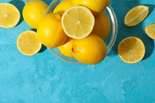 Чаша с лимонами на синем фоне, вид сверху. Спелые плоды
 - Фото, изображение
