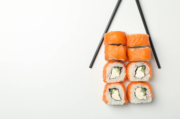Chopsticks and sushi rolls on white background, space for text - Photo, Image
