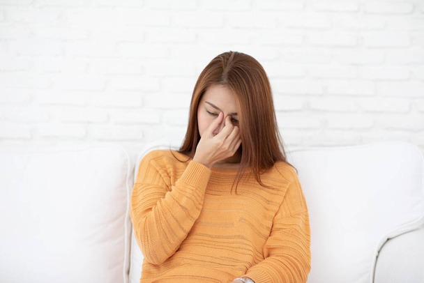 Femme asiatique assis sur le canapé ont un mal de tête et Migraine se sentir si stressé, Healthcare Concept
 - Photo, image