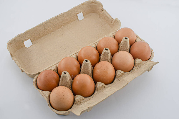 View of ten brown chicken eggs in an open egg carton isolated on white background. Eggs in box - Photo, Image