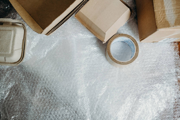 Setting of the delivery box for the customer, online sales, box, tape and  plastic bubbles on wooden table. Online shopping concepts. - Φωτογραφία, εικόνα