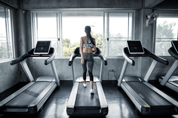 Sexy asijské ženy cvičení na běžícím stroji v tělocvičně. Cvičení žen v tělocvičně zdravé. Pojetí zdravotní péče s cvičením v tělocvičně. Krásná dívka hraje fitness v tělocvičně. - Fotografie, Obrázek