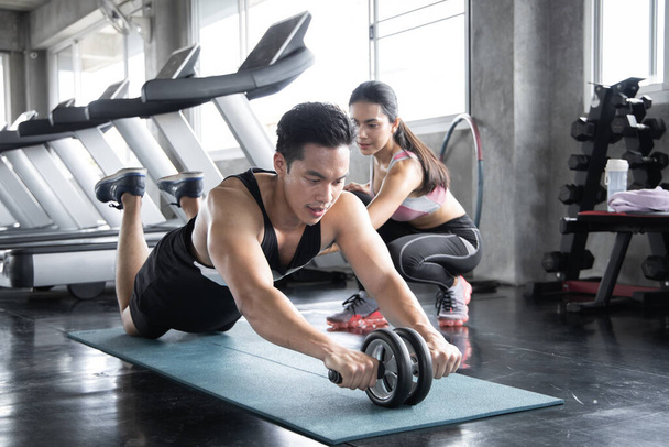 Bonito treino asiático por ab roda no tapete de ioga exercício com mulher são treinadores no ginásio. Conceito de exercício na academia
. - Foto, Imagem
