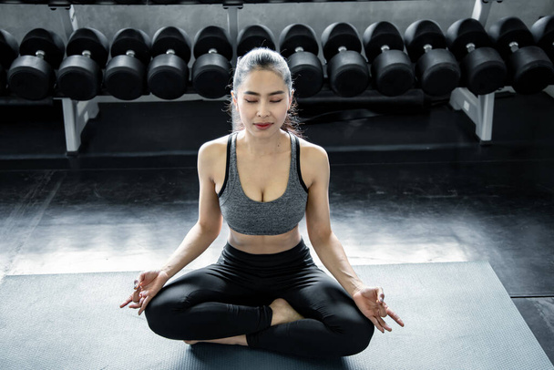 Seksowna Azjatka grająca w jogę na siłowni. Koncepcja ćwiczeń na siłowni. Kobieta trening jogi na macie. - Zdjęcie, obraz