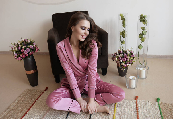 a beautiful gentle girl in silk satin pajamas at home, she is cozy and comfortable, she is resting and working at home. - Fotoğraf, Görsel