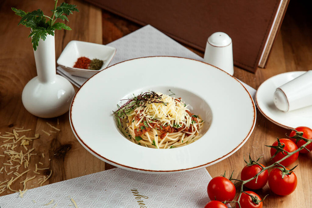 vista lateral pasta boloñesa con tomates de queso sal y pimienta sobre la mesa
 - Foto, Imagen