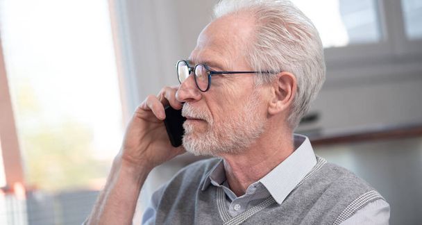 Portret van senior zakenman praten op mobiele telefoon - Foto, afbeelding