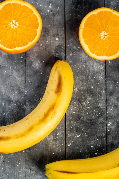 sliced in half orange and banana on a wooden table - Valokuva, kuva