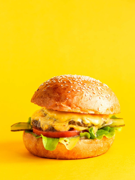 side view cheeseburger with double patty and cheese  tomato  lettuce leaf  sauce and pickled cucumber in burger buns jpg - Foto, Bild