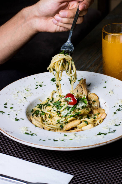pasta with chicken tomatoes greens and grated cheese served with juice - 写真・画像
